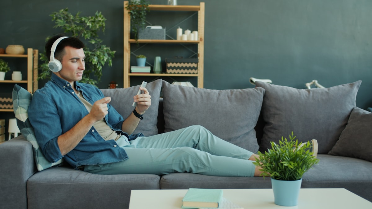Bluetooth LE Audio kullanımını temsil eden kablosuz kulaklık ve akıllı telefon kullanan kişi